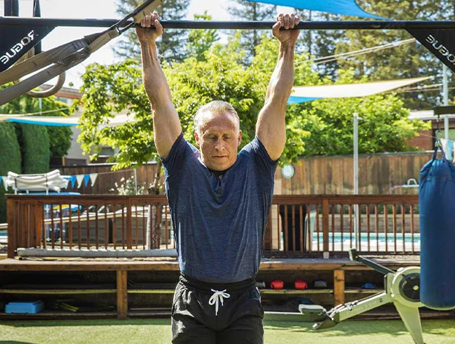 Forma member doing a pull-up hang outdoors